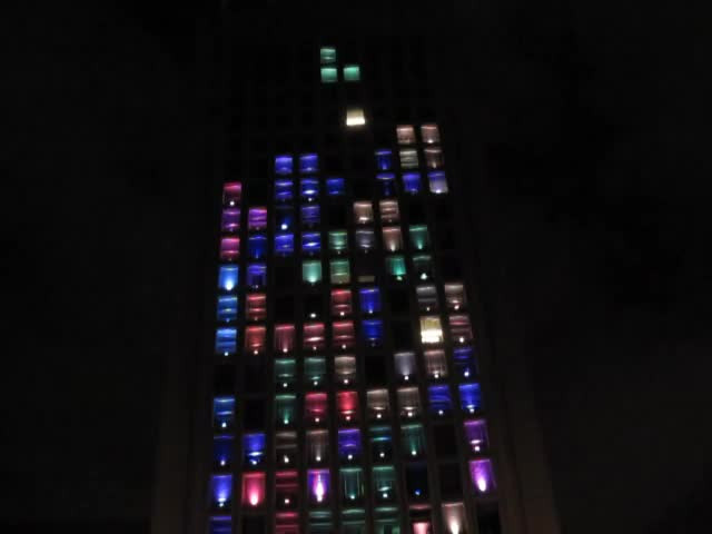 Тетрис из света, который исходит из окон многоквартирного дома.